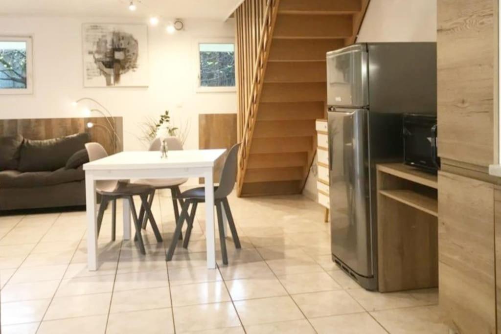 Il comprend une cuisine équipée d'une table blanche et d'un réfrigérateur. dans l'établissement Entre nous à la Riviera des Alpes, à Aix-les-Bains