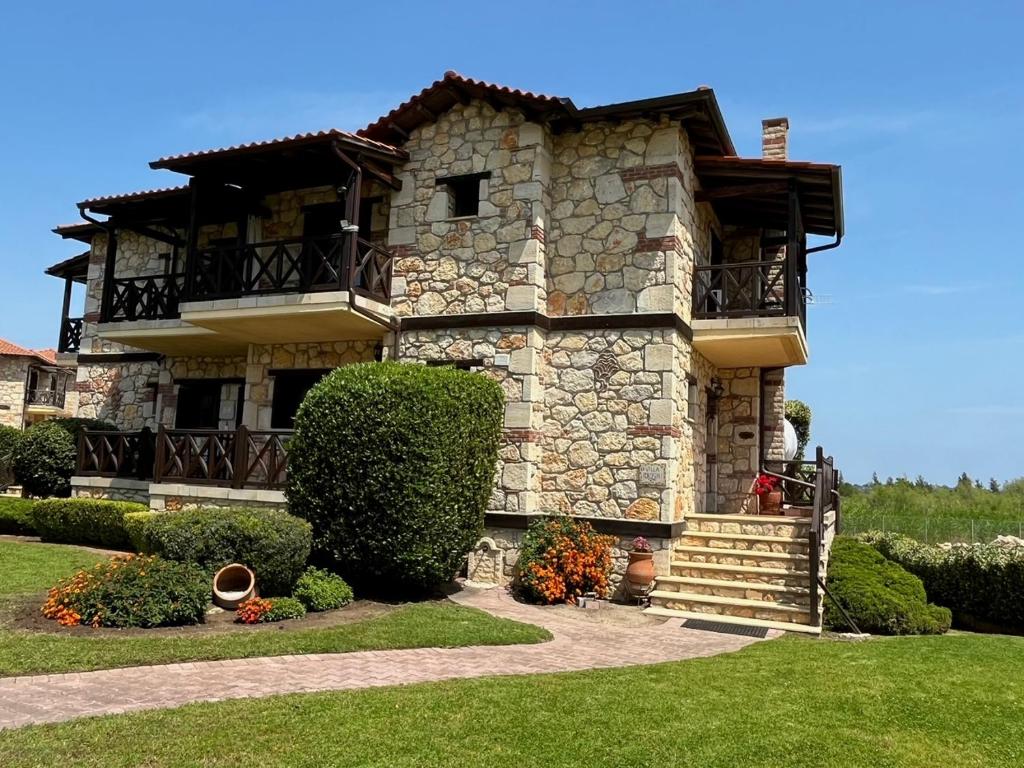 a large stone building with a balcony on top at Villa Rokosini in Vourvourou