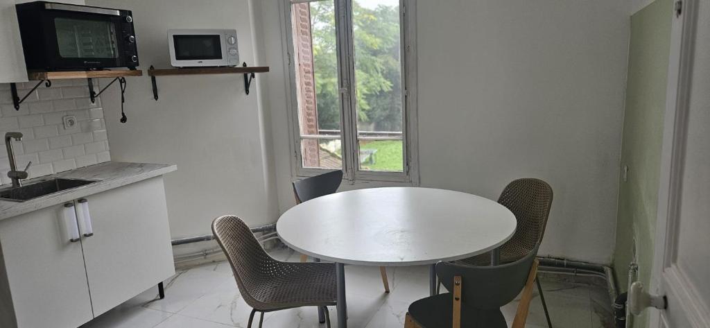 une cuisine avec une table et des chaises blanches ainsi qu'une fenêtre dans l'établissement Villa d athis, à Athis-Mons