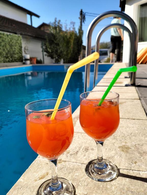 two drinks sitting on a table next to a swimming pool at Casa Gabrielle in Călimăneşti