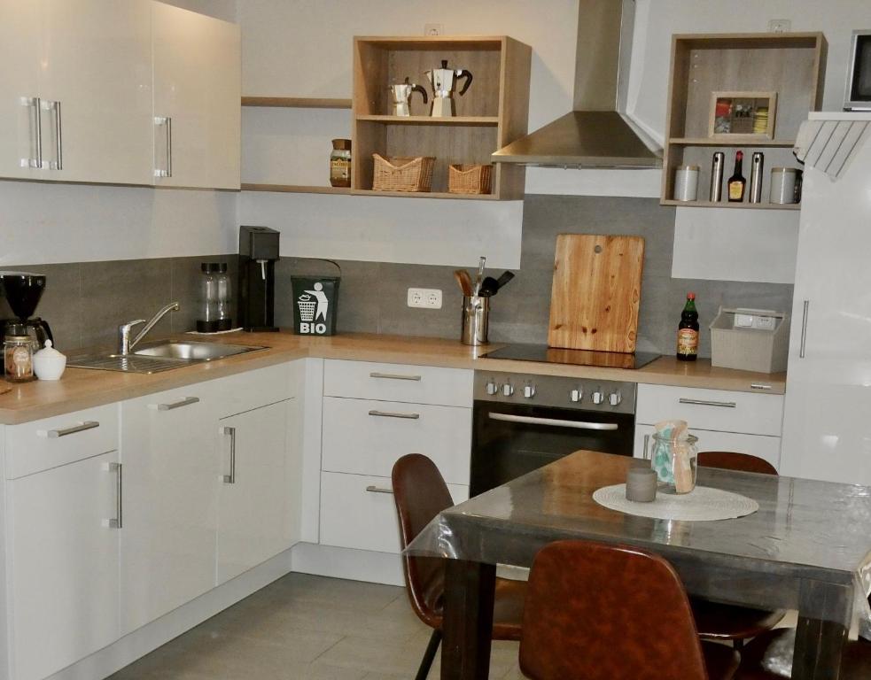 a kitchen with white cabinets and a table and a sink at Kleine Milchbar Barrierefrei in den Bergen auf dem Hof Grindelborn in Mürlenbach