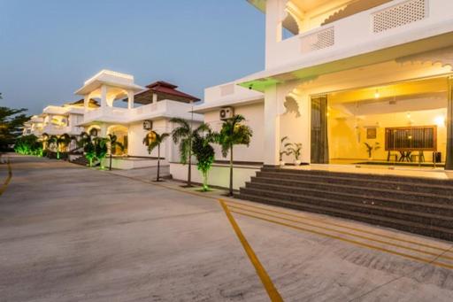 a large white building with stairs and a building at BA-NA Hills Resort in Salara
