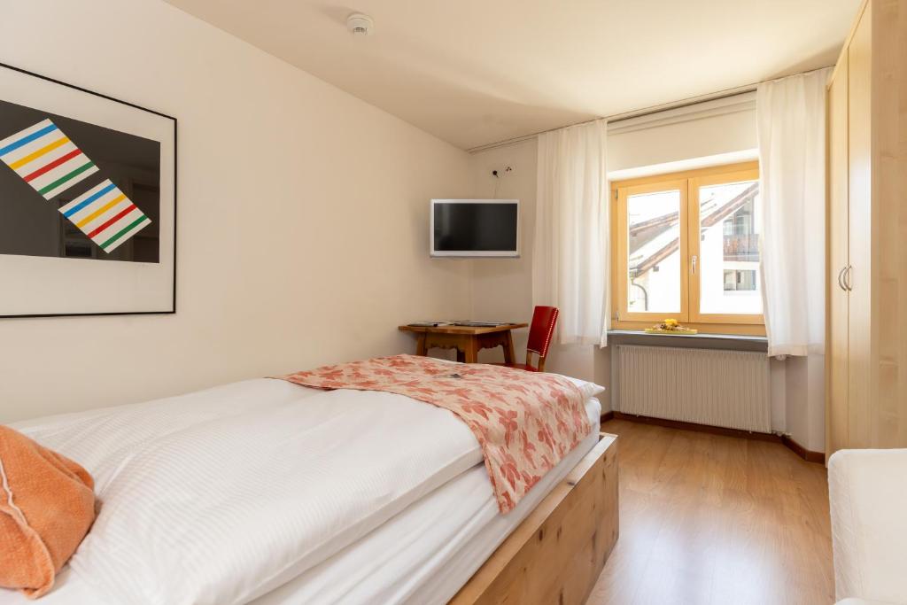 a bedroom with a bed and a tv on the wall at Palazzo Mysanus Samedan in Samedan