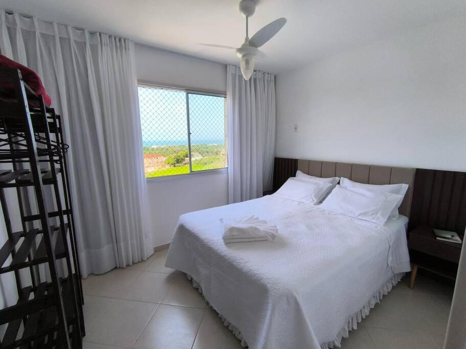 una camera da letto con un letto bianco e una finestra di Apto Inteiro - Com roupa de cama e banho - Elevador - Garagem - Wi-fi - Vista Mar de todas as janelas e varanda a Guarapari