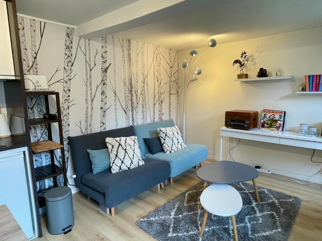 a living room with a blue couch and a table at Maisonnette dans jardin partagé in Colombes
