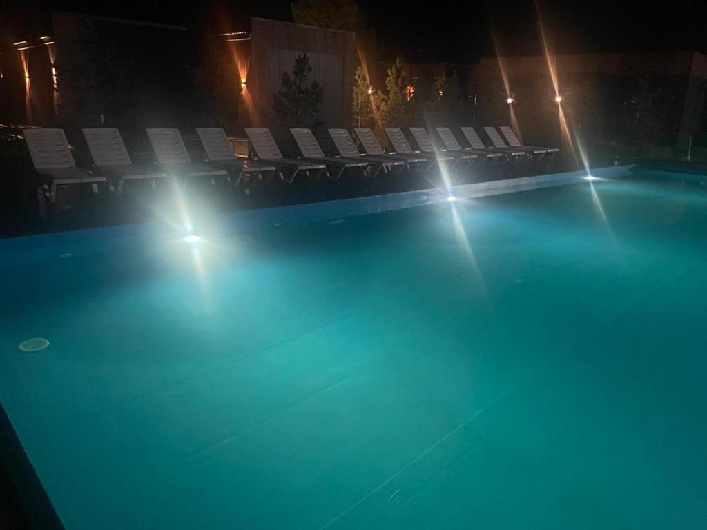 a swimming pool at night with chairs and lights at Atyrau Avenue in Vorobʼyëvka