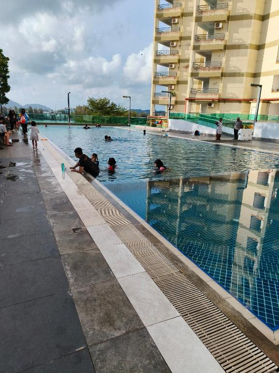 a group of people swimming in a swimming pool at Marina Heights Apartment in Lumut
