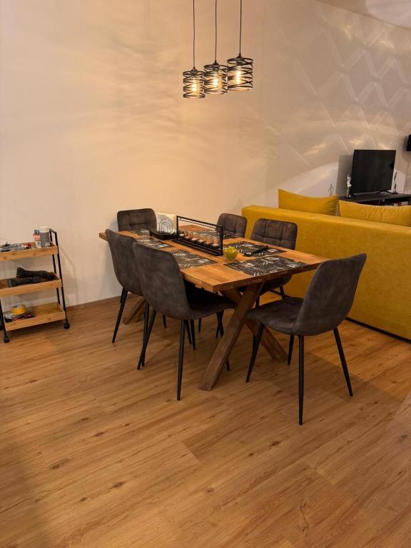 a dining room table with chairs and a yellow couch at Schönbrunn Garden Apartments in Vienna