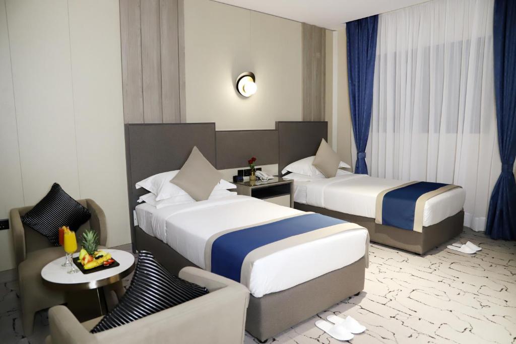 a hotel room with two beds and a chair at فندق اطلاله الشمس in Tabuk