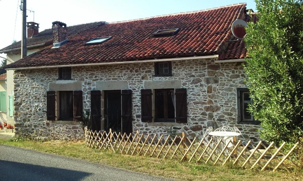 une ancienne maison en pierre avec une clôture en bois devant elle dans l'établissement La Croix De Camargue, à Oradour-sur-Glane