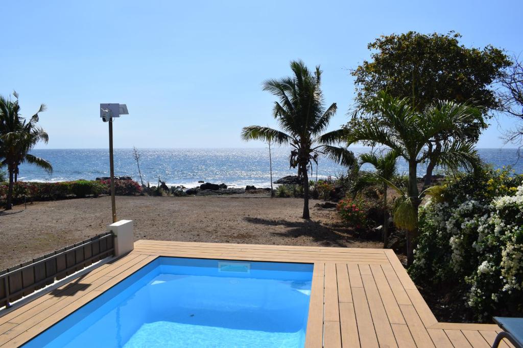 a swimming pool next to a beach with the ocean at Le Rocher Sea Front Villa in Flic-en-Flac