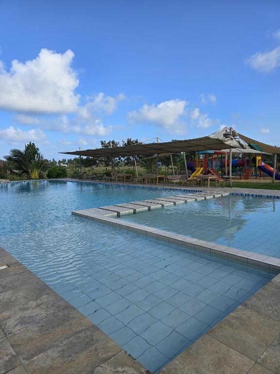 a large swimming pool with a playground in the background at The Vipingo Retreat in Vipingo