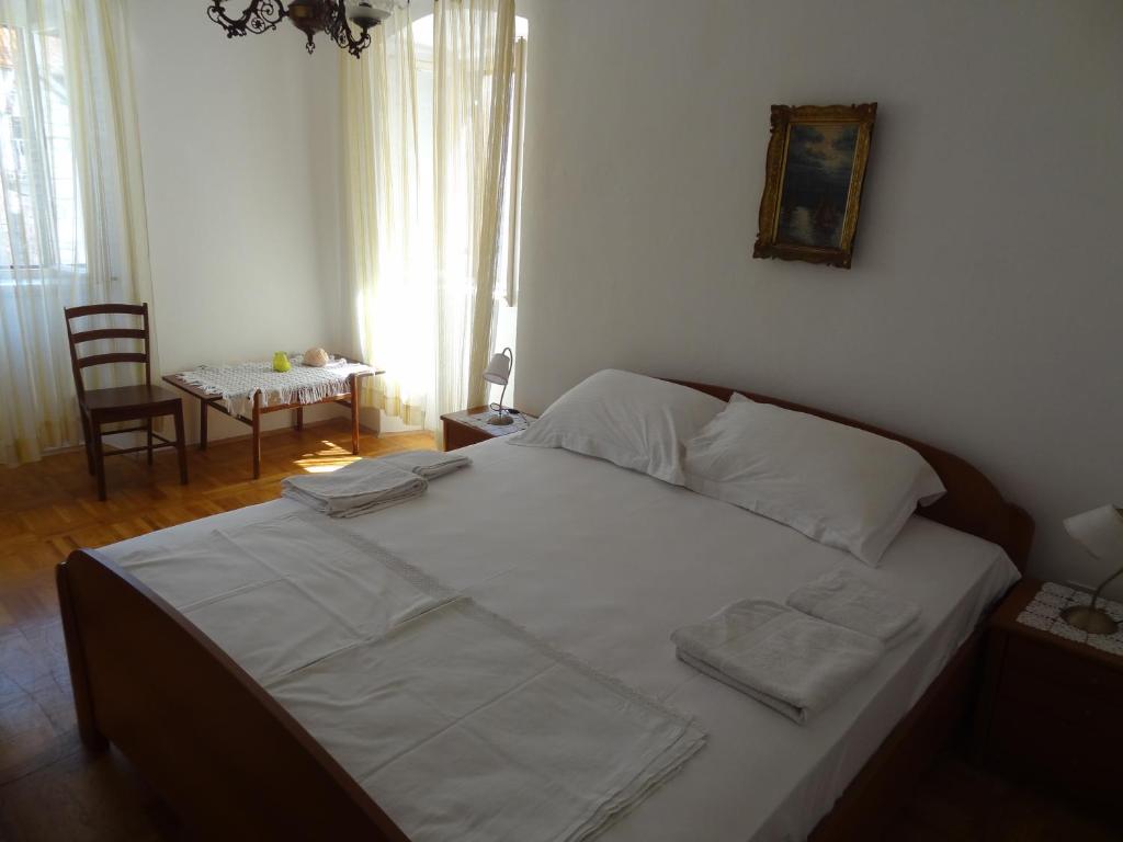 a bedroom with a bed with white sheets and a table at Inn Town Center in Hvar