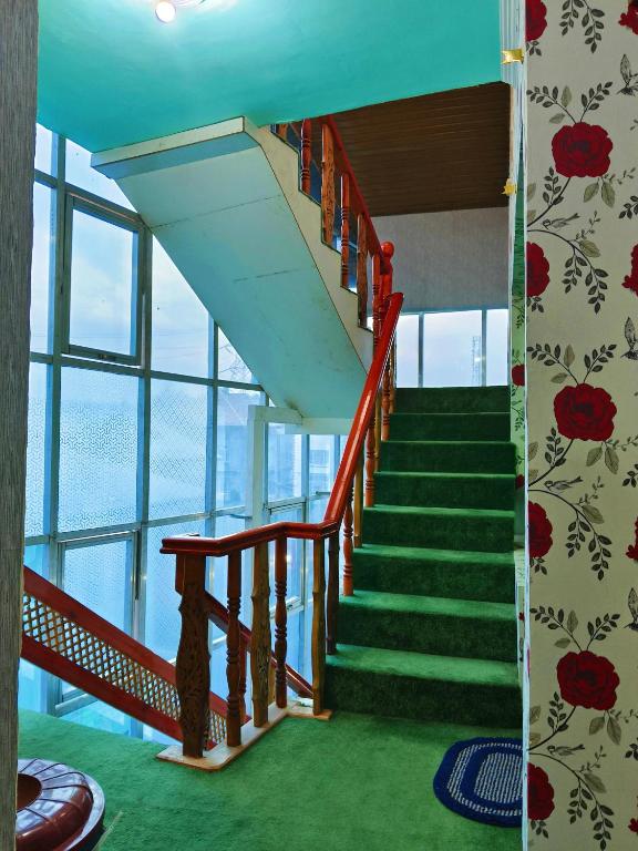 a staircase in a building with green carpet and windows at Luminaire Homestay in Srinagar
