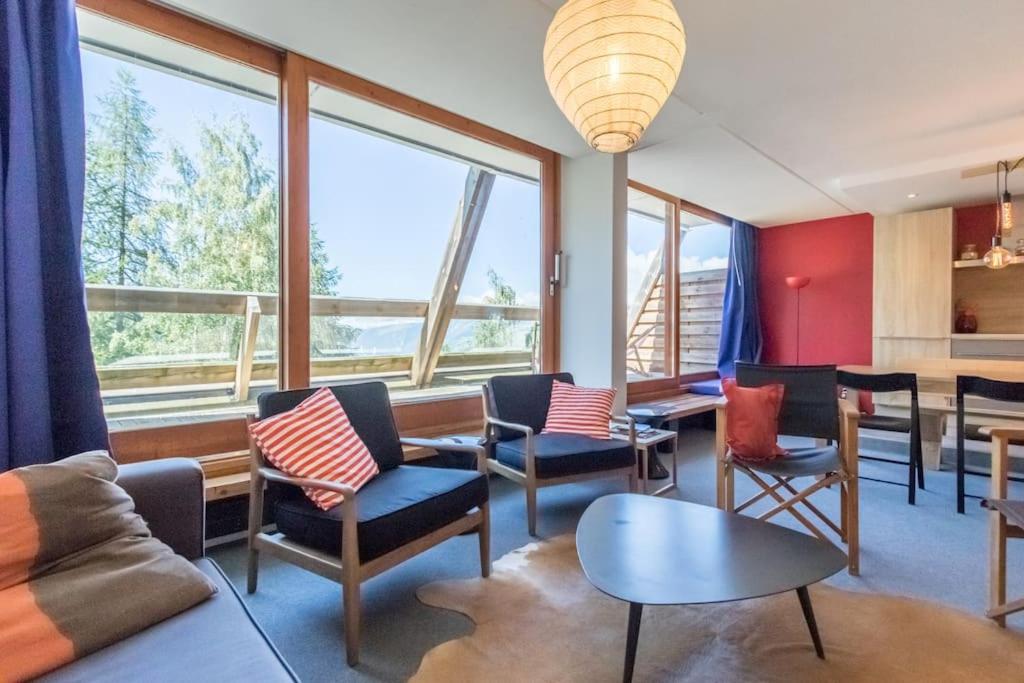 un salon avec des chaises, une table et des fenêtres dans l'établissement La belle de la Cascade 8 pers - Arcs 1600 station, à Bourg-Saint-Maurice