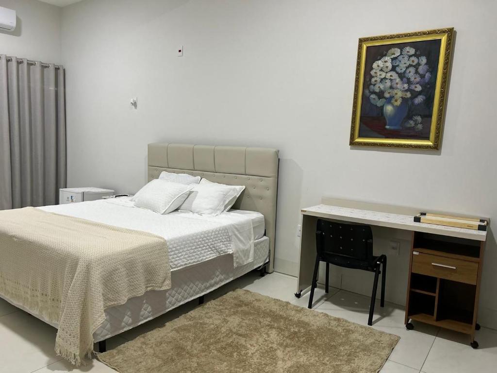 a bedroom with a bed and a desk with a picture at Madeira Lofts - Centro Juina in Juína