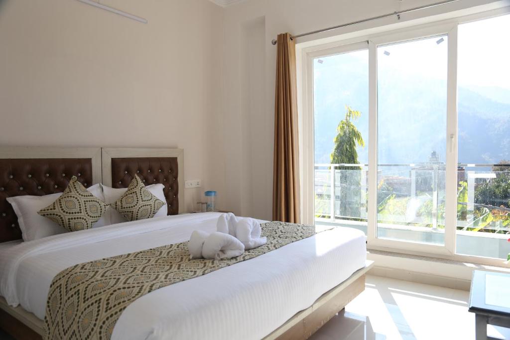 una camera da letto con un letto grande e una grande finestra di Hotel yog tapovan MOUNTAIN VIEW ROOM a Rishikesh