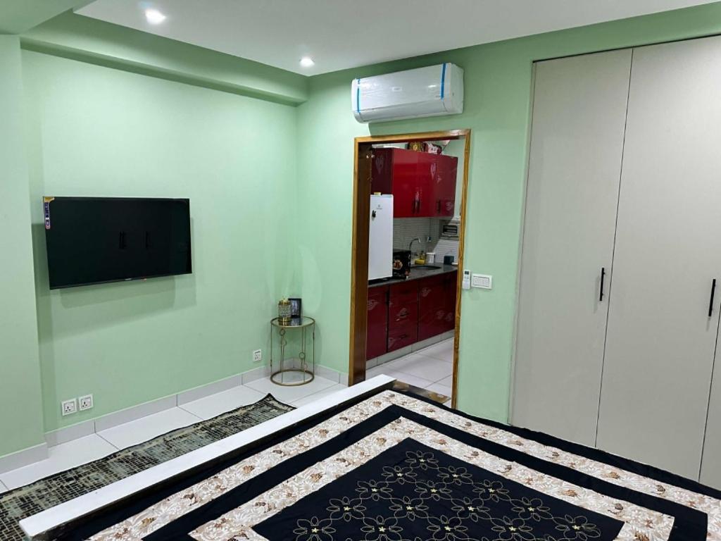 a room with a bed and a television on a wall at Broadway Living in Rāmkot