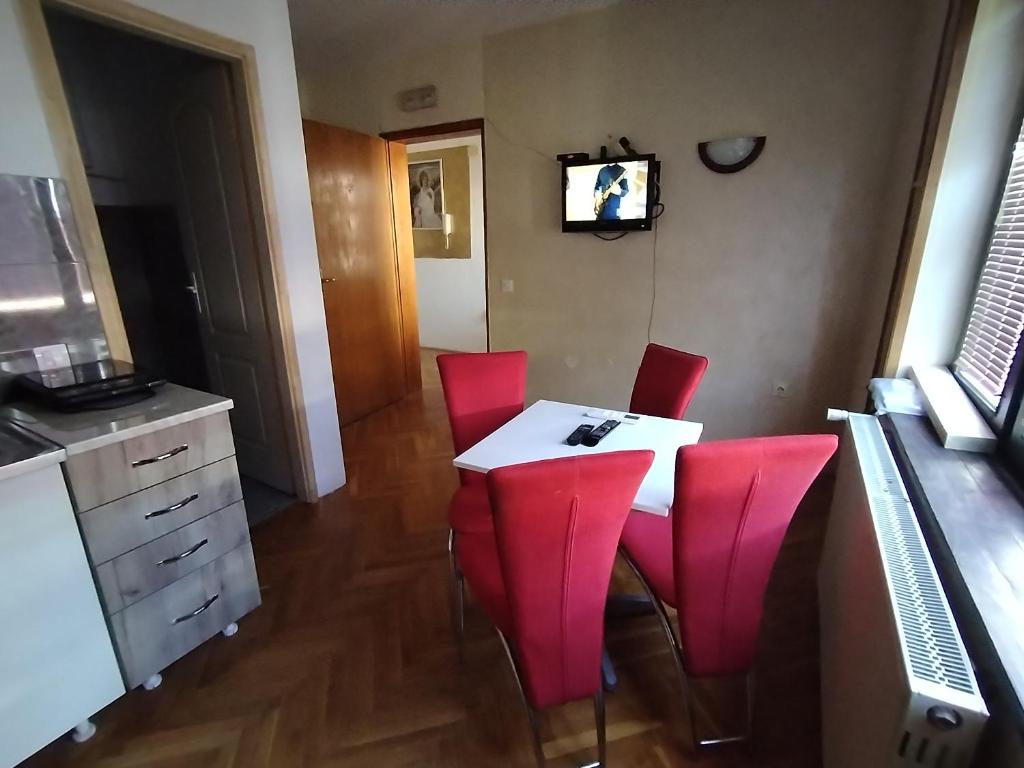 Habitación con mesa con sillas rojas y TV. en Stan na dan Iva 5, en Užice