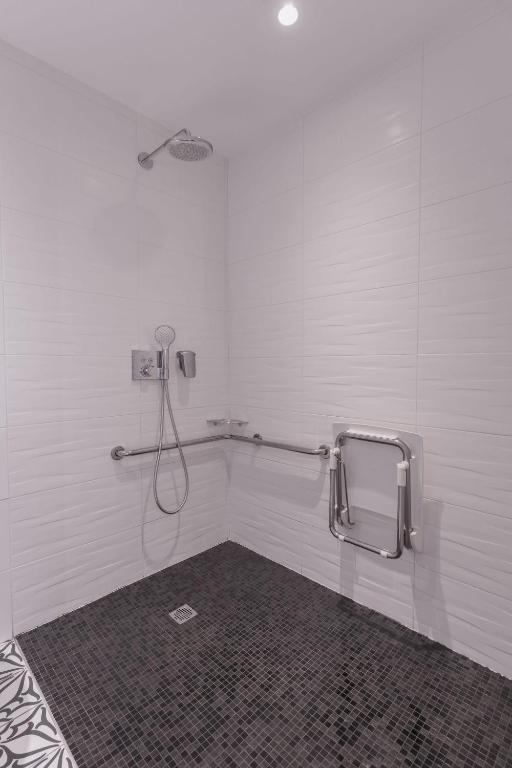 a bathroom with a shower in a white wall at Le Cornouaille Hotel & Spa in Bénodet