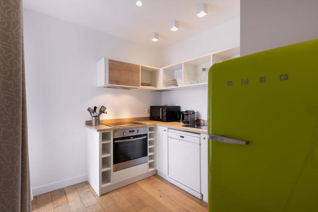 a kitchen with white cabinets and a green refrigerator at Le Cornouaille Hotel & Spa in Bénodet