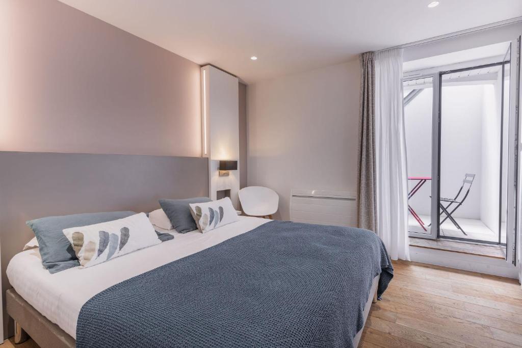 a bedroom with a large bed and a large window at Le Cornouaille Hotel & Spa in Bénodet