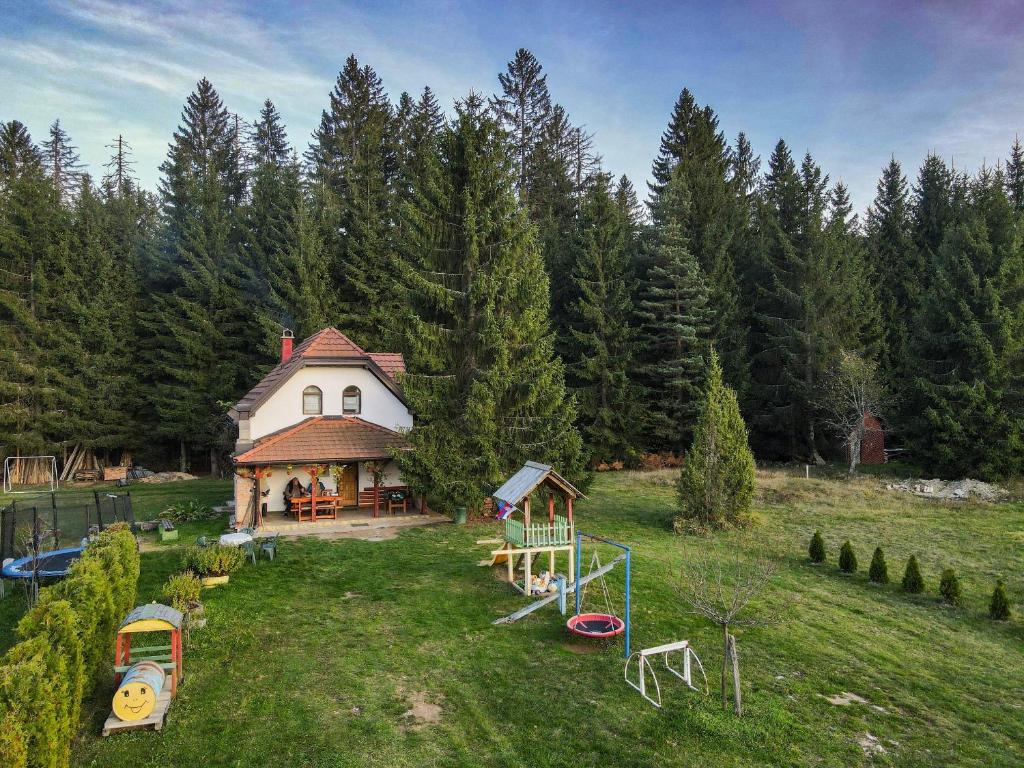 a house with a playground in a field with trees at Vacation home Miki in Bajina Bašta