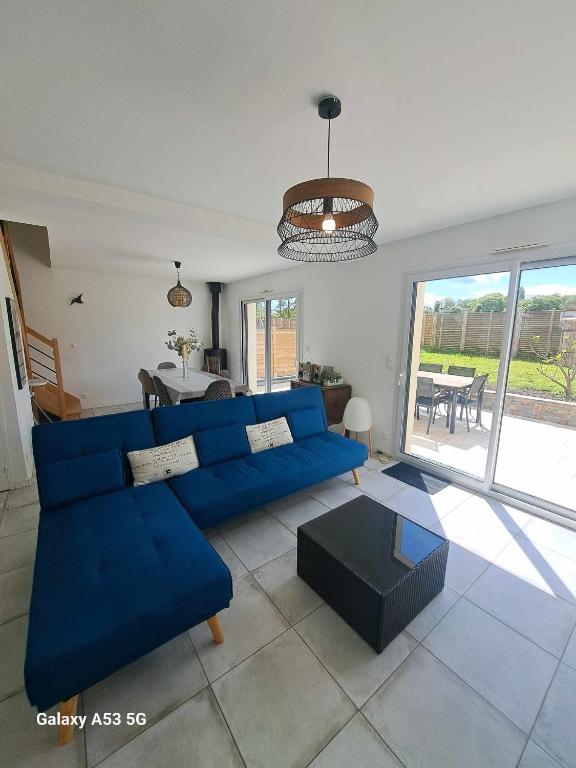 un salon avec un canapé bleu et une table dans l'établissement Maison à Orgères, à Orgères