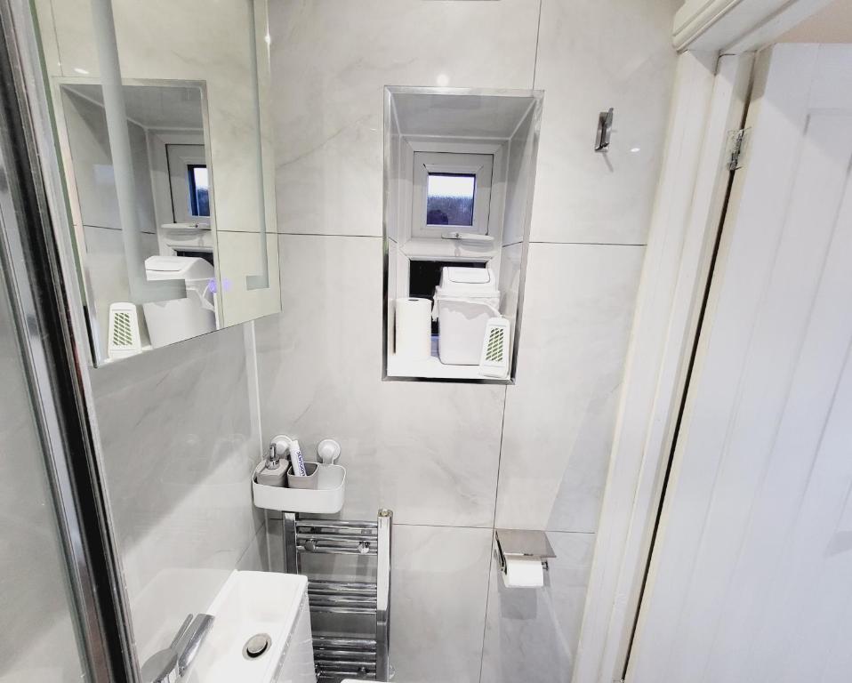 a white bathroom with a sink and a mirror at Nest & Rest En-Suite in Ashford