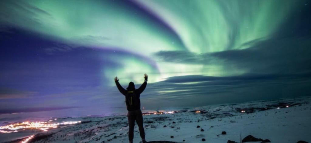 een persoon die op een heuvel staat met zijn handen in de lucht bij Kroken 3 in Gravdal