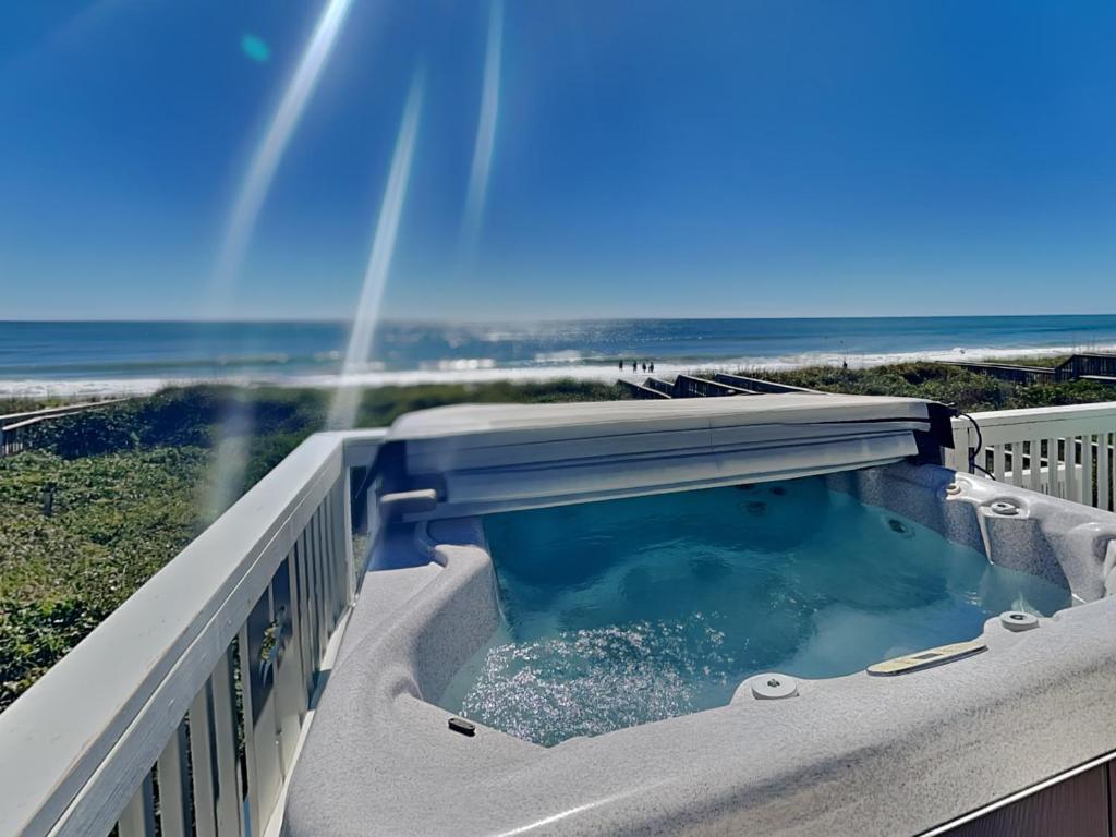 a hot tub on a balcony with the ocean in the background at Sea the Love in North Topsail Beach