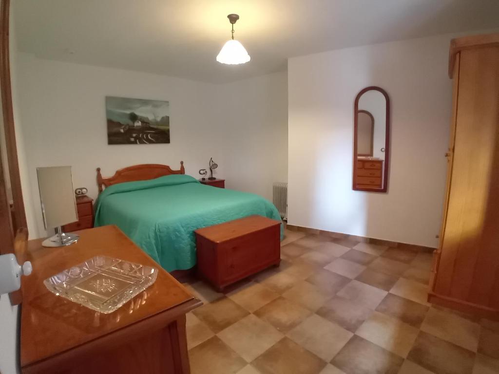 sypialnia z zielonym łóżkiem i stołem w obiekcie Stone Cottage O CEBREIRO w mieście Curtis
