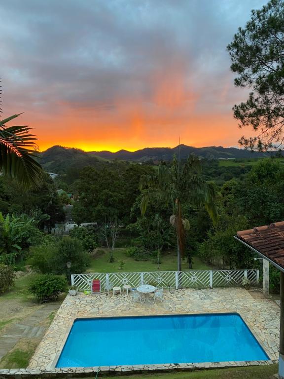 a swimming pool with a sunset in the background at Suite na Casa Azul in Socorro