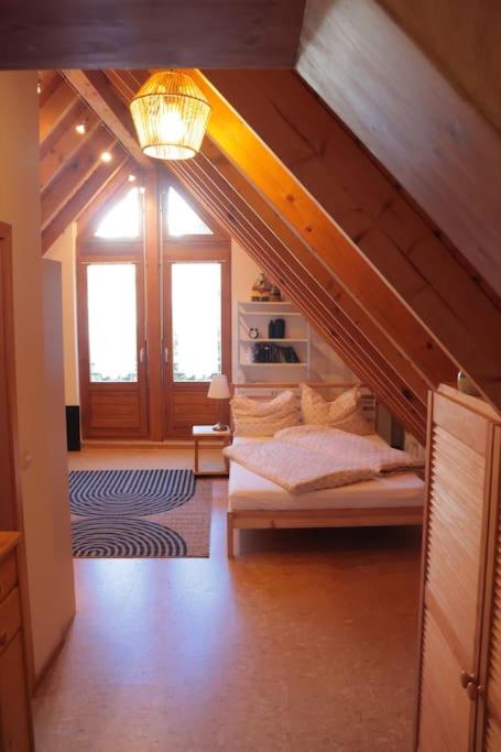 a attic room with a bed and a staircase at Apartment "Karibuni" im Wanderparadies in Sasbachwalden