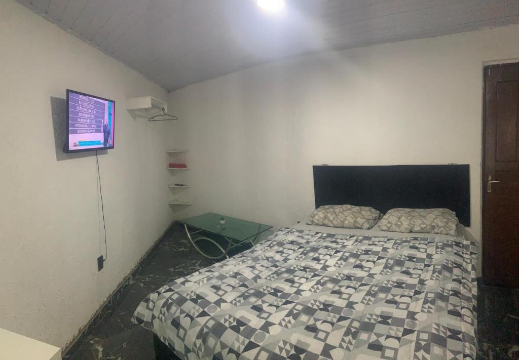 博阿维斯塔Suíte privada com estacionamento的一间卧室，墙上有一张床和一台电视