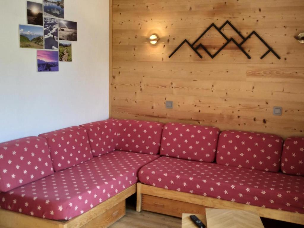 - un canapé rouge dans une chambre dotée d'un mur en bois dans l'établissement Résidence Pierre De Soleil - Studio pour 4 Personnes 39, à Mâcot La Plagne