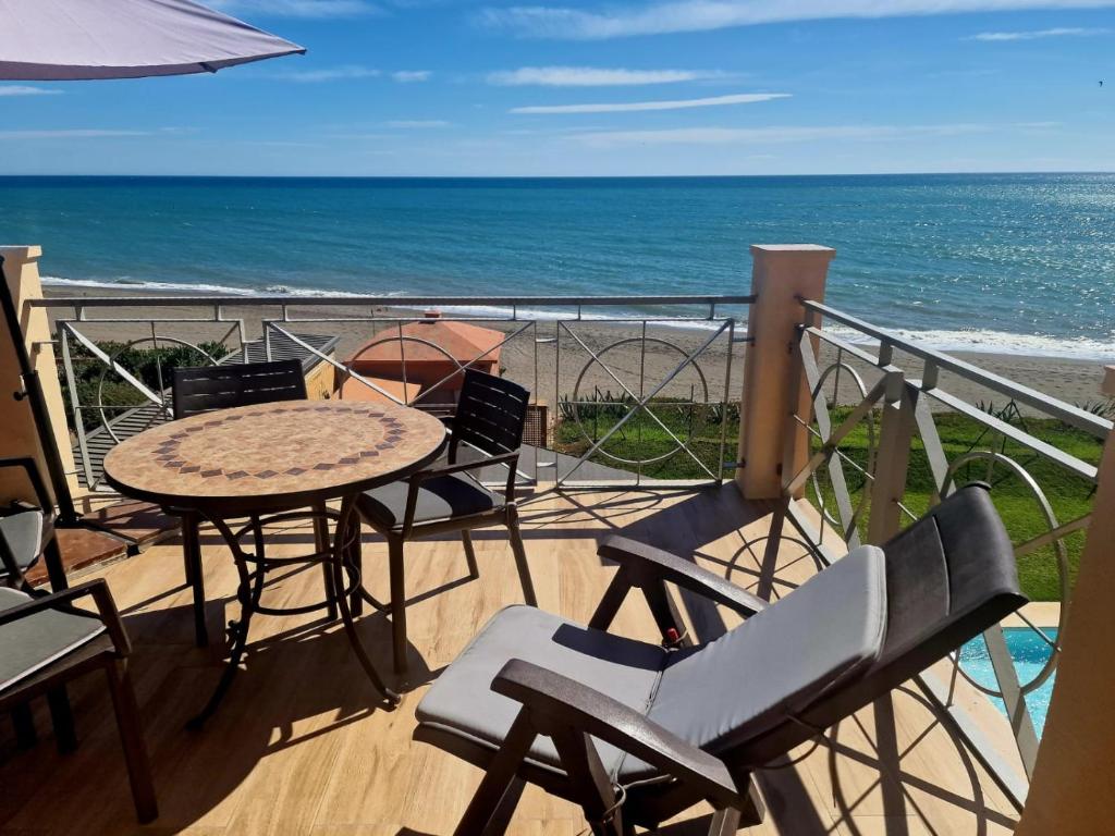 a balcony with a table and chairs and the ocean at Exclusive Beachfront Penthouse in Almayate Alto
