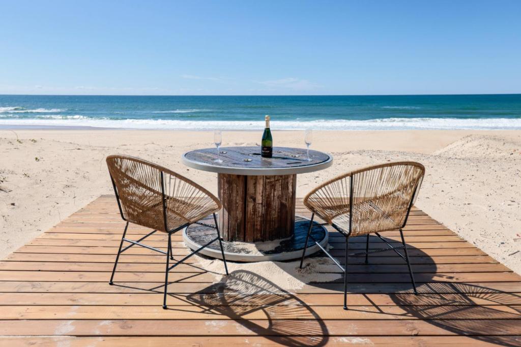 - une table avec une bouteille de vin et 2 chaises sur la plage dans l'établissement Huchet, à Moliets-et-Maa