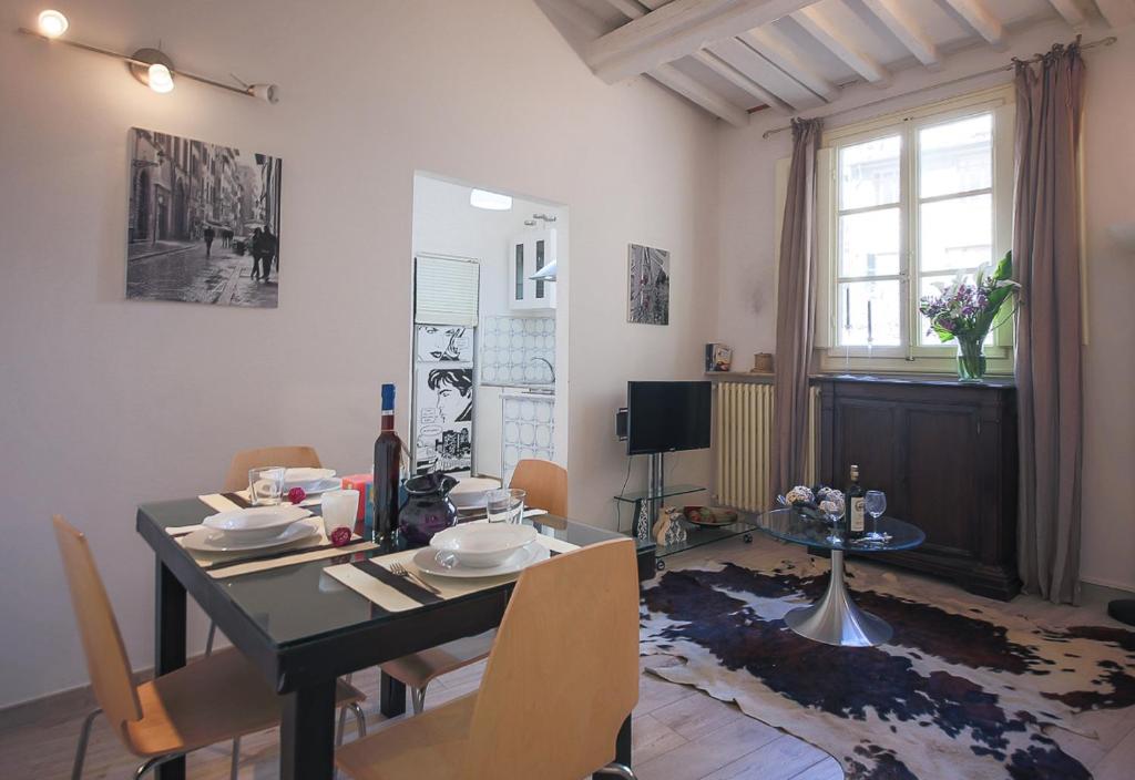 ein Esszimmer mit einem Tisch, Stühlen, einem Tisch und einem Fenster in der Unterkunft Apartments Florence Pandolfini Roof in Florenz
