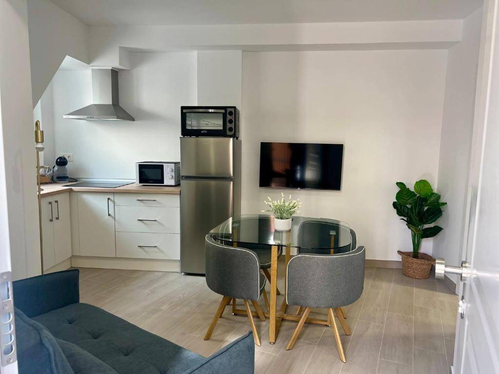 a kitchen with a glass table and a refrigerator at Apartamento Turístico Centro Antequera B in Antequera