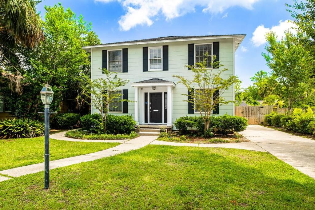a white house with a black door at East Hill Manor with 2 Kitchens Near Beach & Downtwn in Pensacola
