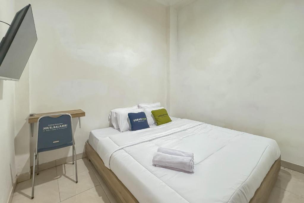 a white room with a bed with two pillows on it at Urbanview Hotel Maharani Garut in Cireungit