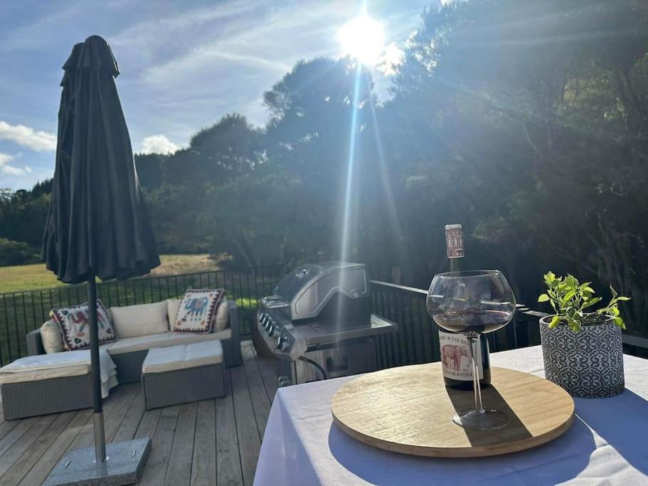 un tavolo con un bicchiere di vino e un ombrellone su un ponte di Haven Creek a Masterton