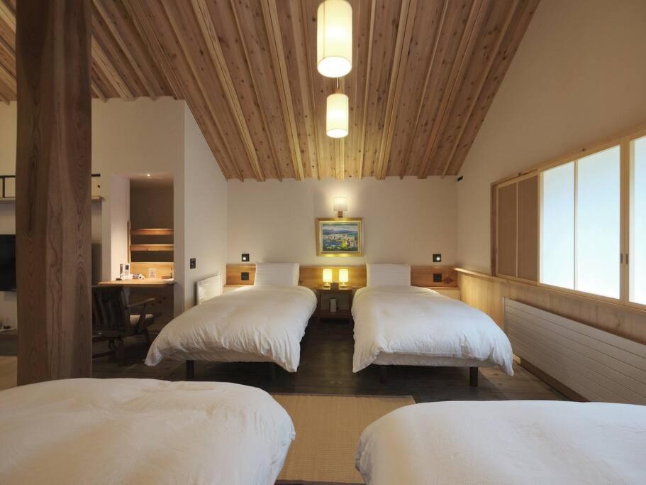 a room with three beds and a desk in a room at Akashi in Hakodate