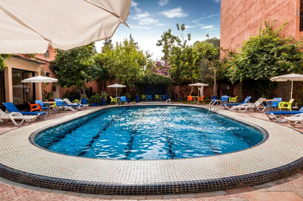 una piscina con sillas y sombrillas en un hotel en Appart-Hotel EZZAHIA by HMS, en Marrakech