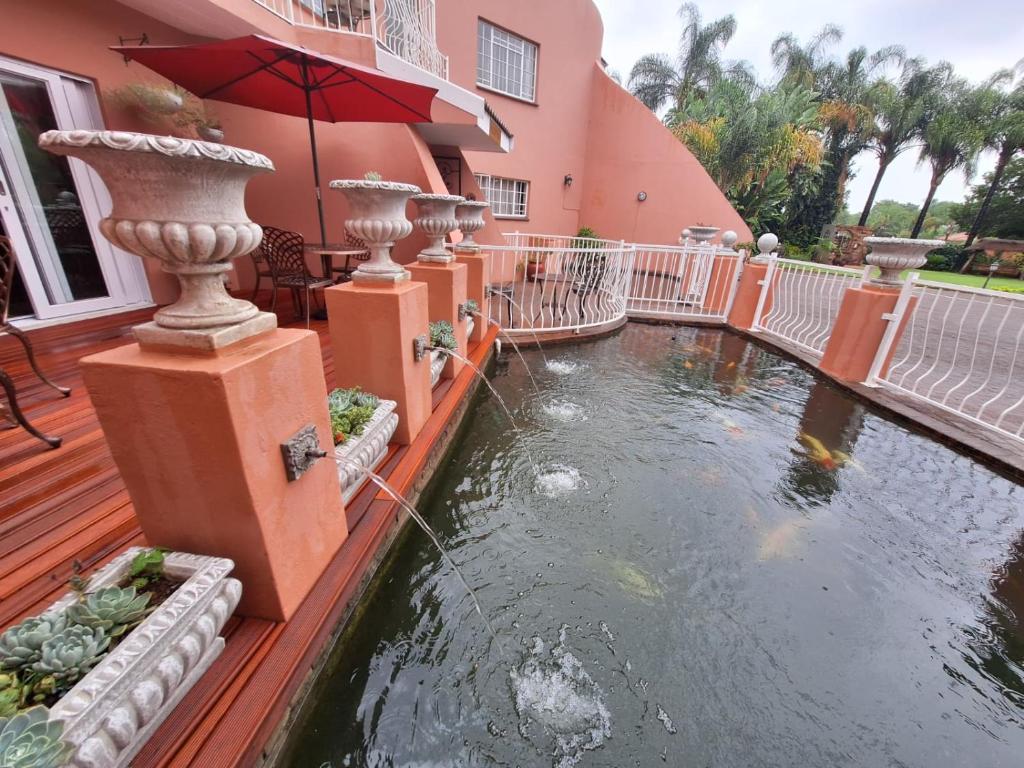 a house with a pond in front of a house at El Gran Chaparral Guest House in Pretoria