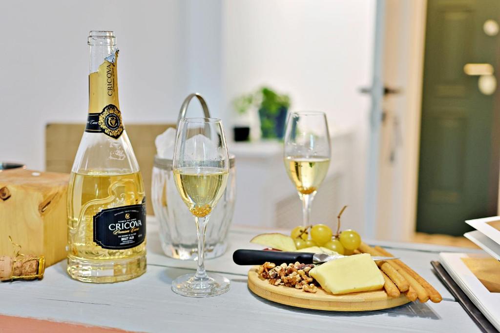 a table with two glasses of white wine and cheese at Art Boutique Residence - City Center - Calea Victoriei in Bucharest