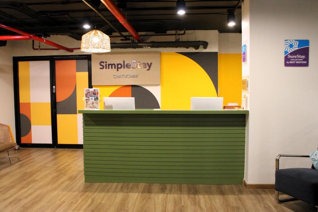A green reception counter set against colorful geometric branding in the hotel lobby.