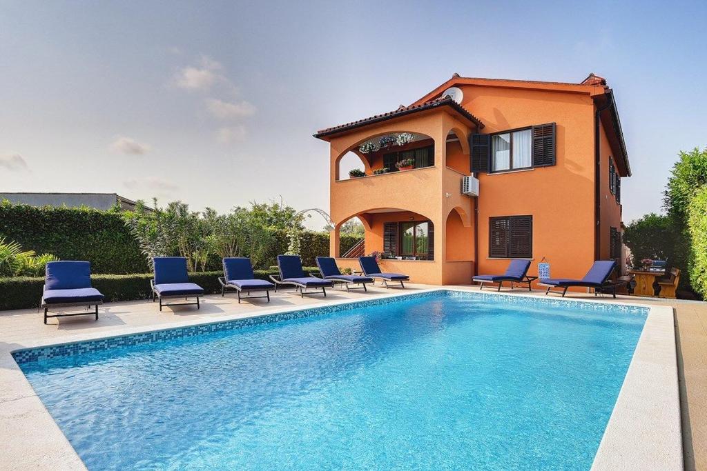 a villa with a swimming pool in front of a house at Apartment Sissano in Ližnjan