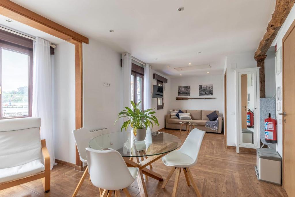 a dining room with a glass table and white chairs at POLITXE Bermeo in Bermeo